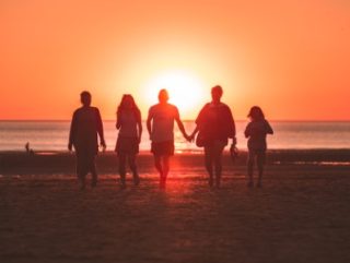 Family walking on the beach during sunset.